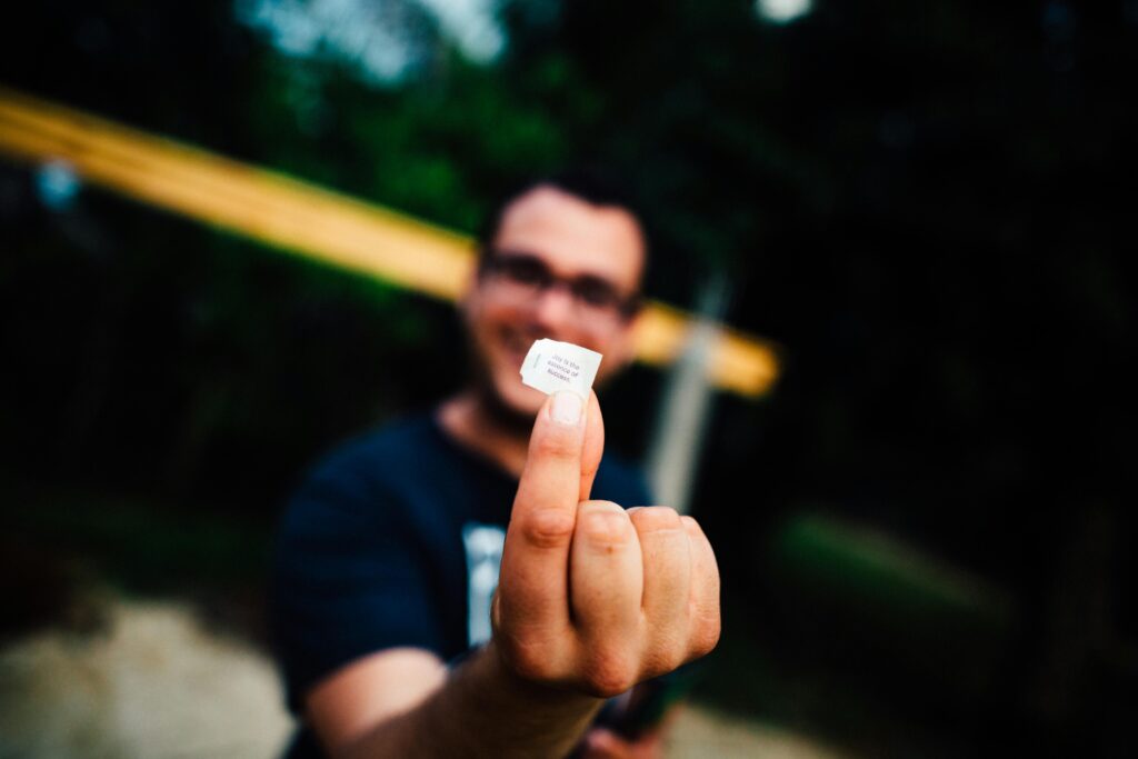 Portrait of a man smiling and holding a SIM card outdoors with focus on the hand.