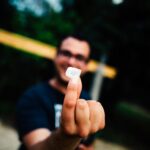 Portrait of a man smiling and holding a SIM card outdoors with focus on the hand.